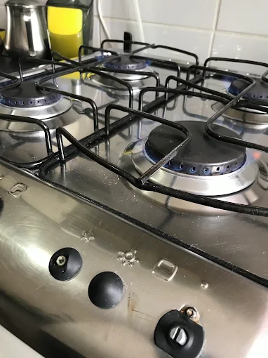 Fogão inox de quatro bocas com botões frontais e queimadores apagados após atendimento técnico